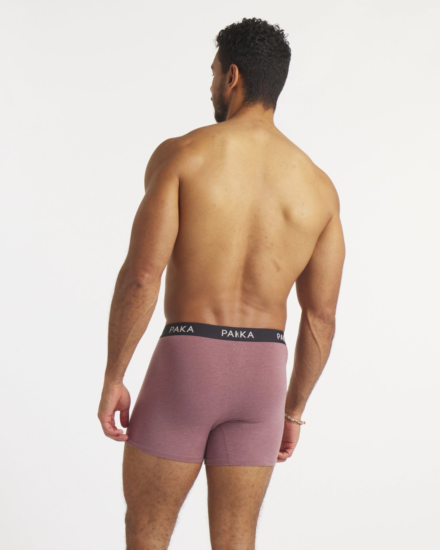 Rear view of Men’s Essential Boxer Brief in mauve showing PAKA waistband and mid-thigh fit on model on white background