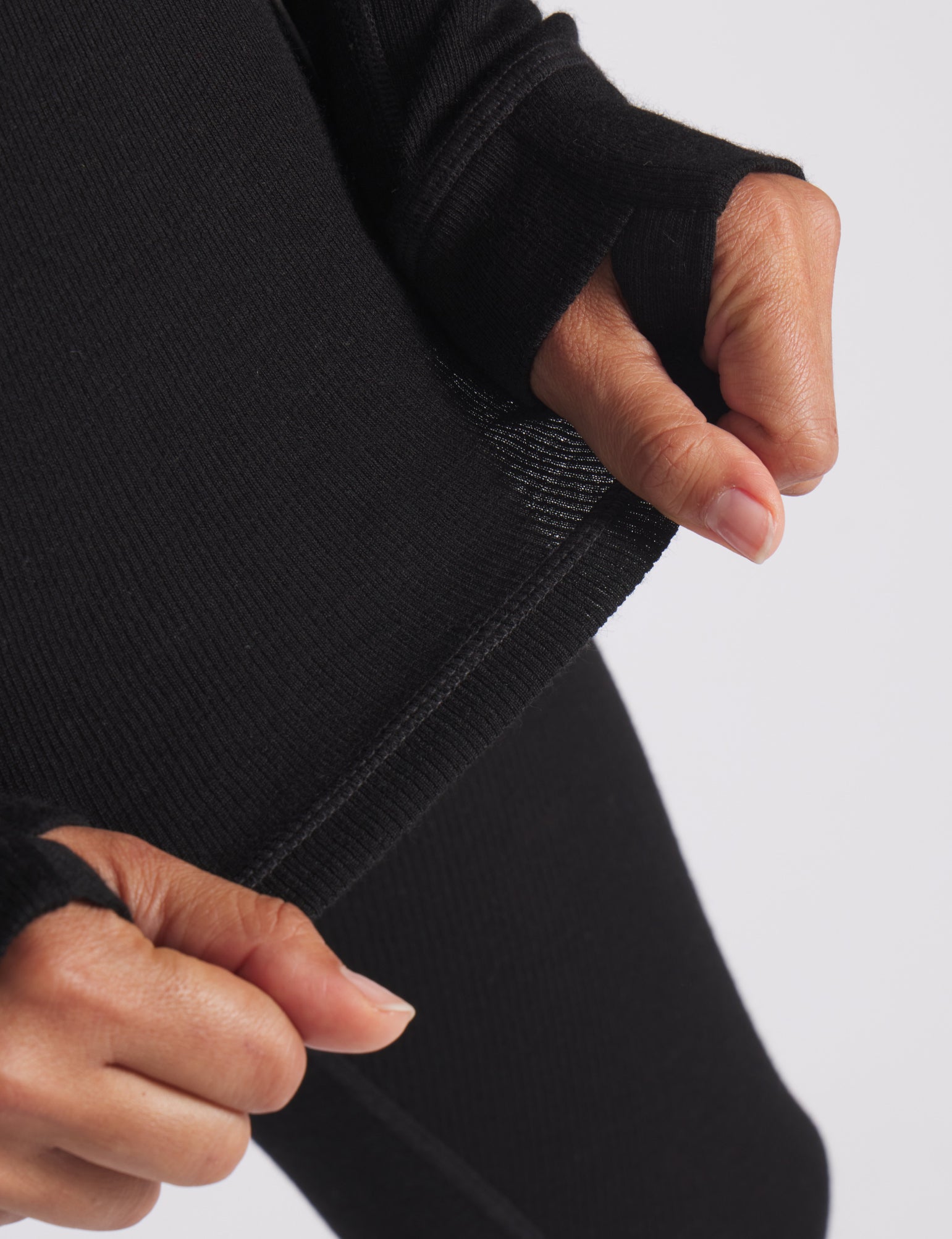 Close-up of black men’s thermal baselayer showing rib knit fabric, flatlock seam, and thumb hole on cuff
