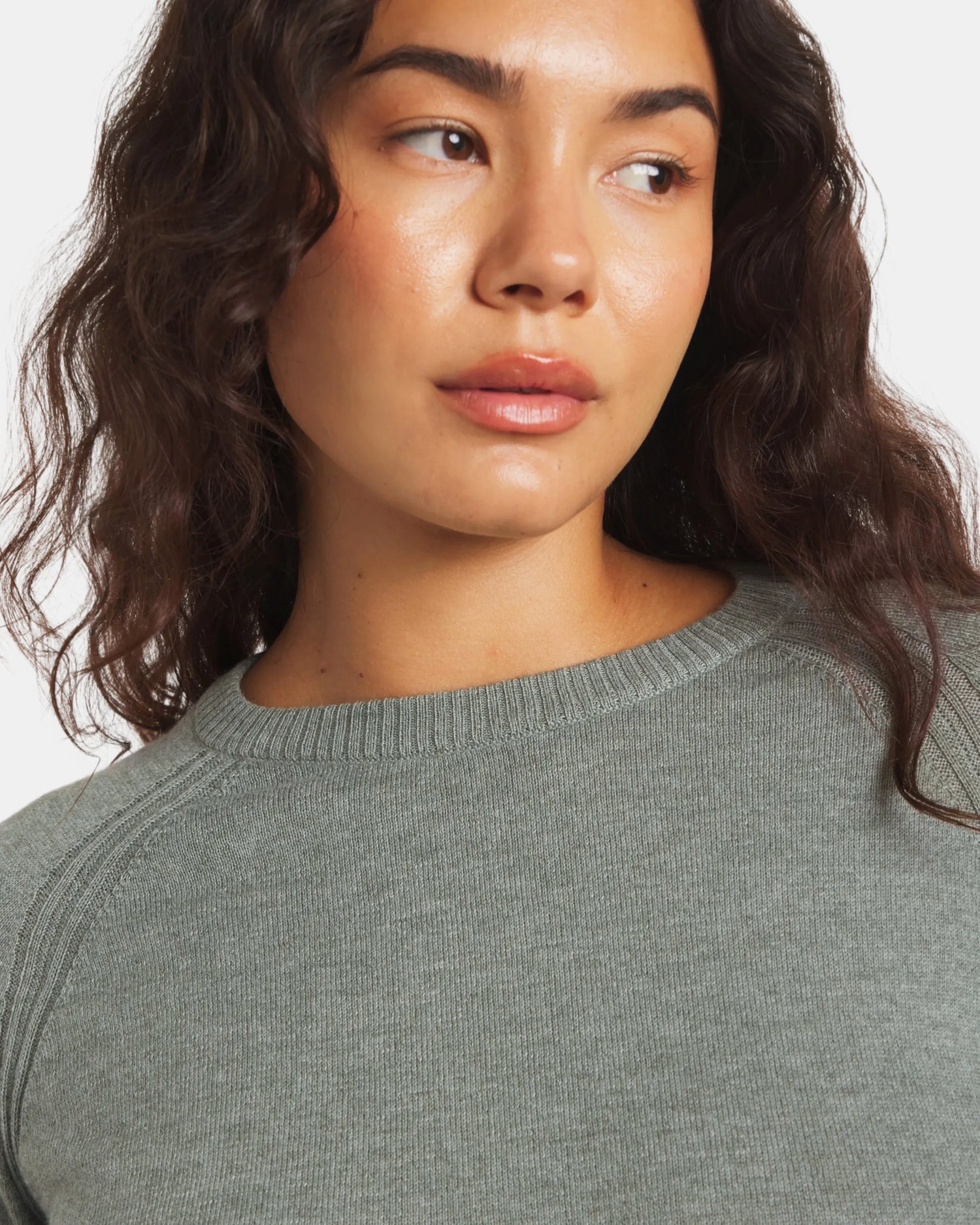 Woman wearing a gray sweater against a white background