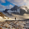 Man with hiking poles walking near the base of Ausangate in the snow. 
