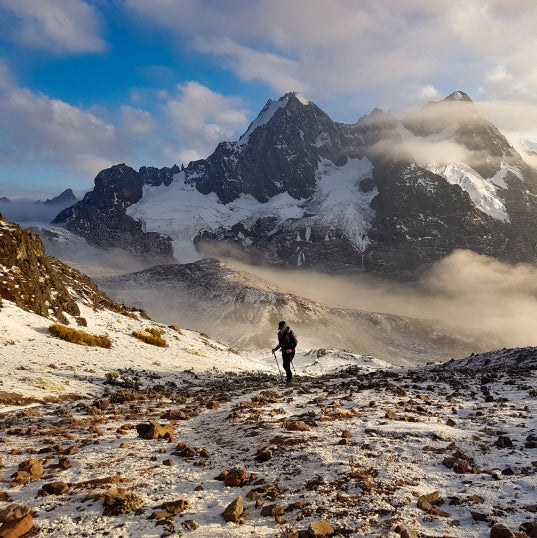 Man with hiking poles walking near the base of Ausangate in the snow. 