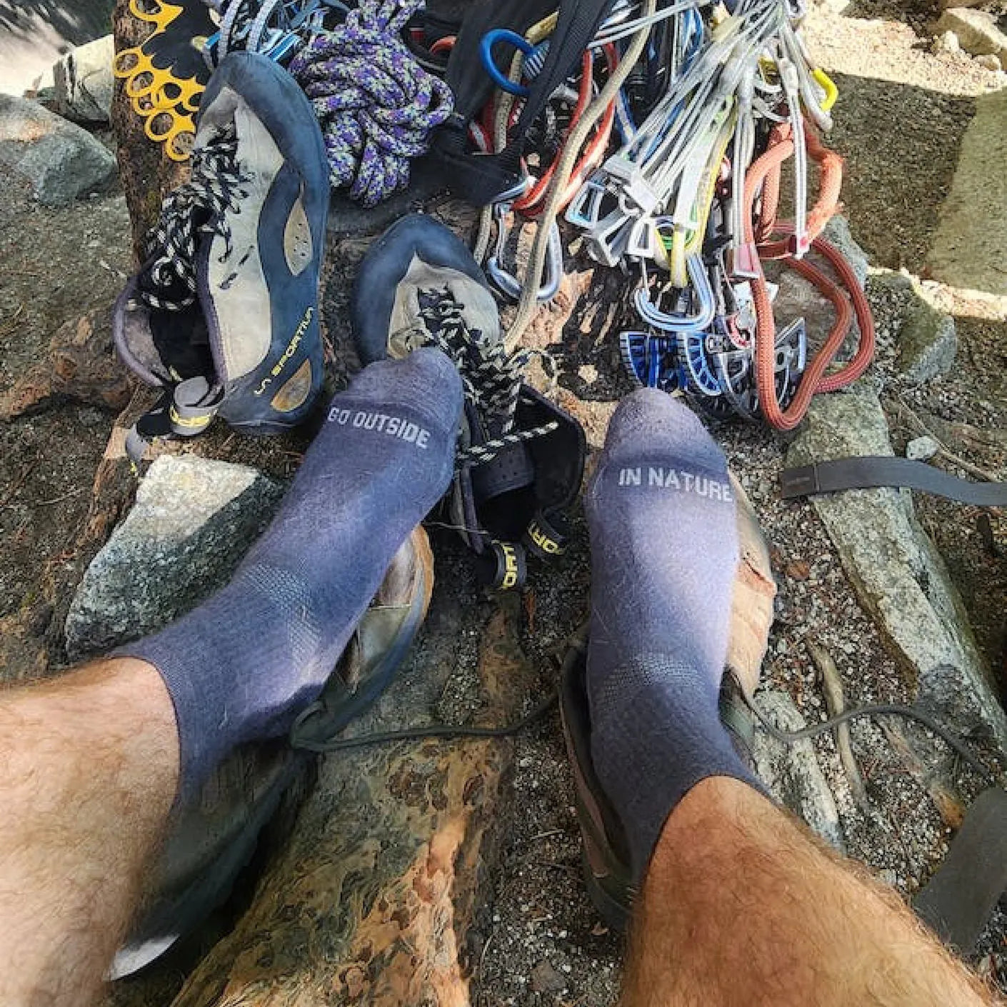 Top view of Trail 3/4 Crew socks on feet showing toe text GO OUTSIDE and IN NATURE with climbing gear on rocks