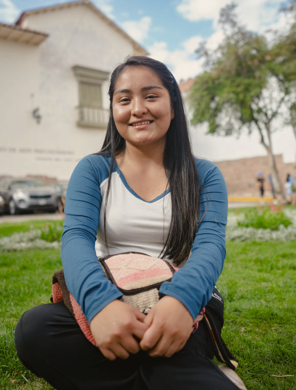 Melany, one of our Paka scholars sitting in the grass and smiling