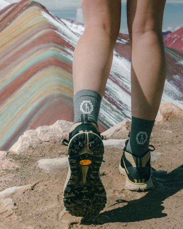 Rear view of Trail crew socks in gunmetal on a model showing ribbed calf grip and padded heel on a rocky trail