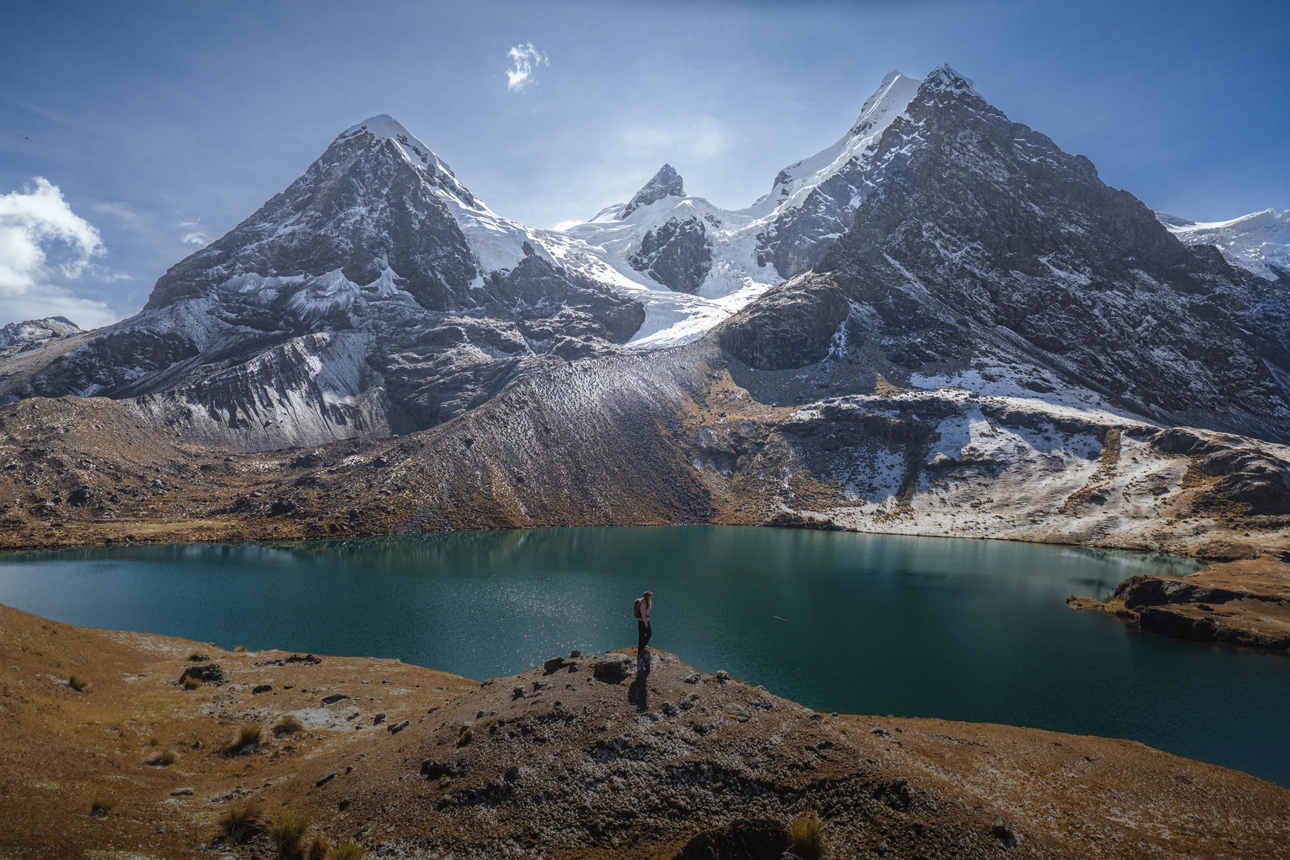 Snow-capped Ausangate peaks towering over a turquoise glacial lake in the Peruvian highlands
