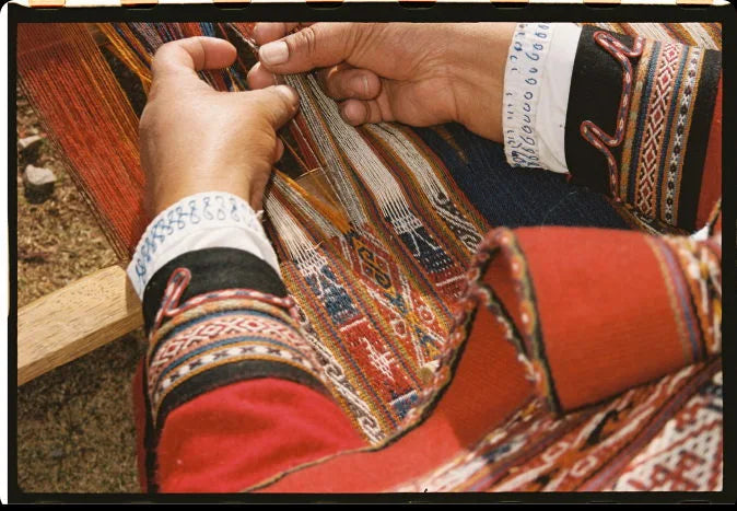 Close-up of a Quechua weaver’s hands weaving a colorful patterned Andean textile on a backstrap loom