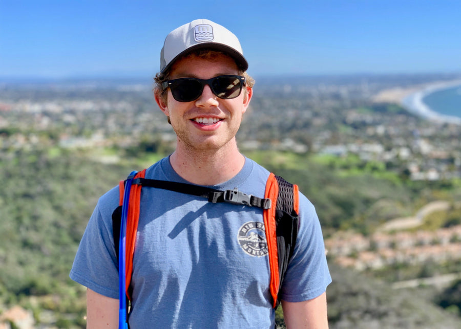 Anders with sunglasses and a backpack standing in front of a scenic view