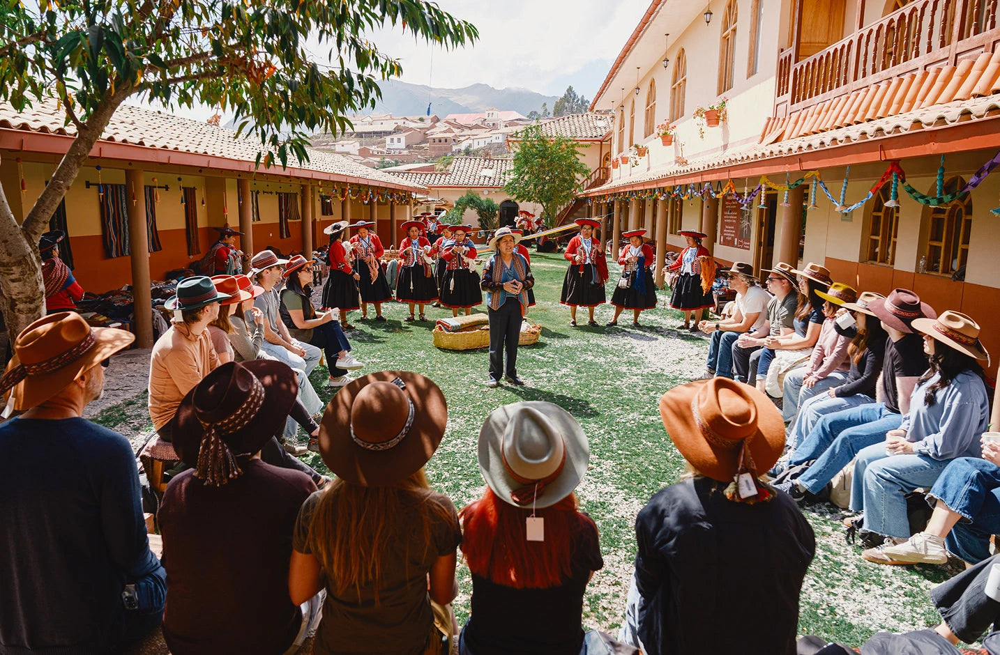 PAKA team gathered in a circle in a sunny Cusco plaza surrounded by colorful colonial buildings and onlookers