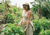 Woman standing in lush Peruvian vegetation wearing a light beige dress and crossbody bag