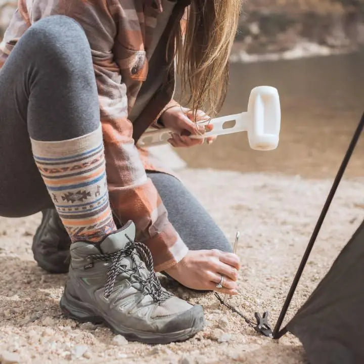 Woman pitching a tent by a river in her cozy alpaca Inca socks