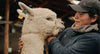 Woman standing outdoors with an alpaca in a mountain landscape promoting PAKAFILL natural fiber insulation