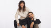 Two models wearing PAKACLOUD alpaca fleece pullovers seated on a light background showing soft brushed texture and relaxed fit