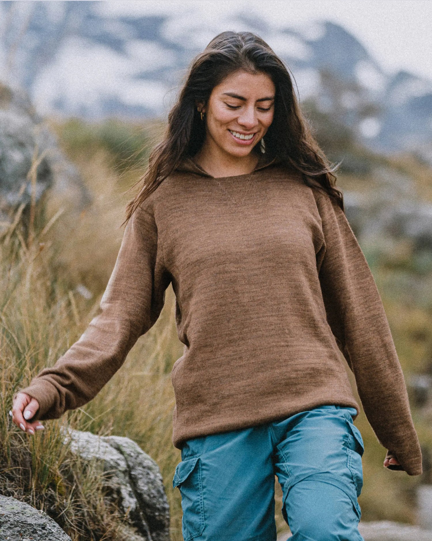 Woman Hiking in The Hoodie Alpaca Hoodie Sweater in Cafe Heather / Brown with Field and Mountains in Background – PAKA Apparel