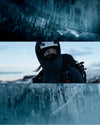 Hiker standing on a glacier edge wearing dark layered outdoor clothing and a backpack, surrounded by towering ice walls