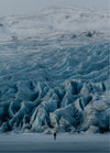Person ice climbing on a blue glacier in Iceland using crampons and ice axes