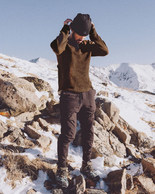 Front view of The Original Crew alpaca crewneck sweater in brown showcasing relaxed fit and raglan sleeves against snowy rocks