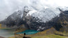 Hiker standing in front of a blue glacial lake at Ausangate