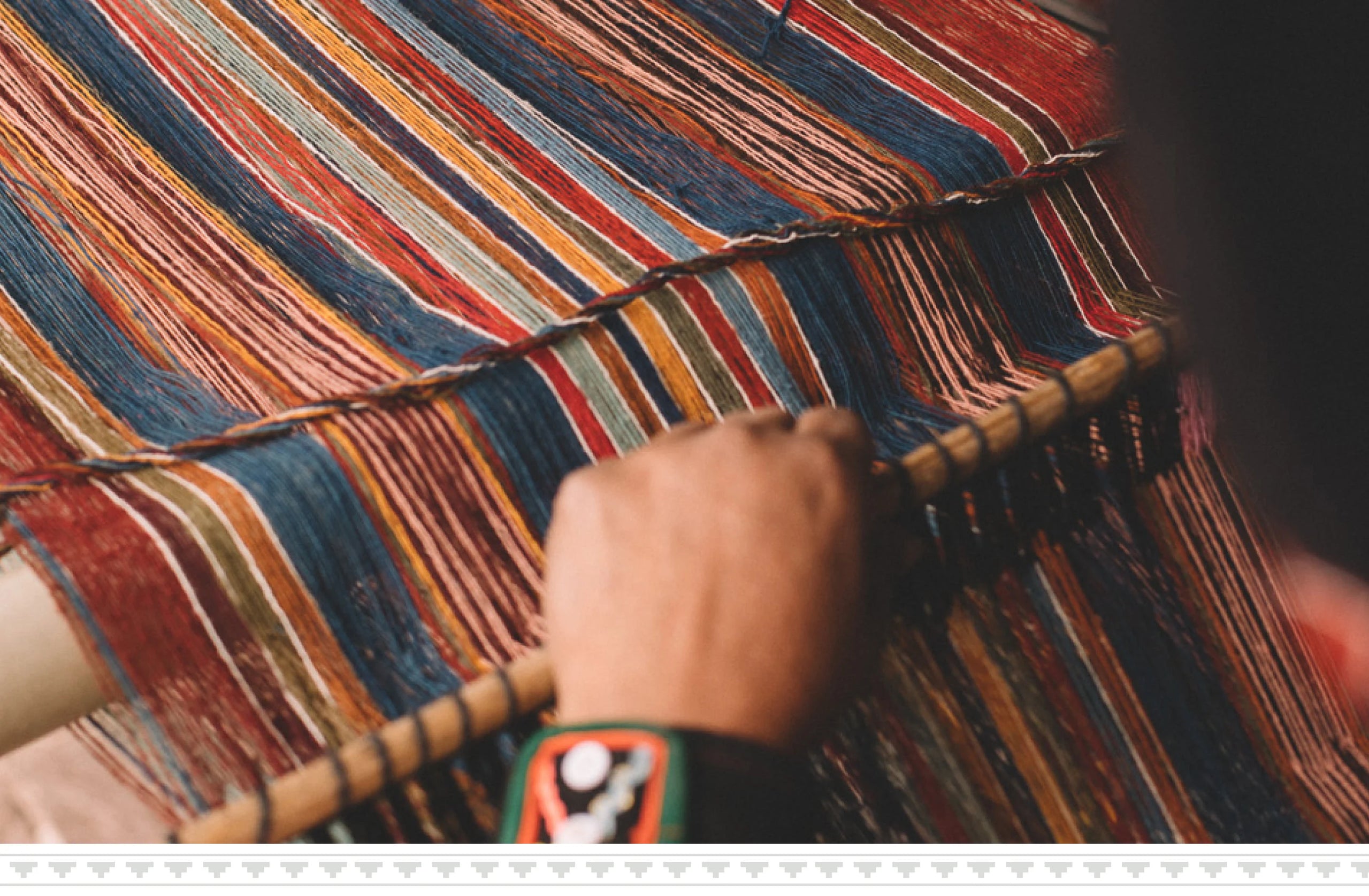 Close-up of hands weaving a multicolored striped Peruvian textile on a loom, highlighting traditional weaving techniques