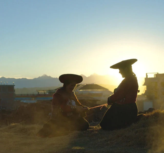 Two quechua women weaving at the sunset 