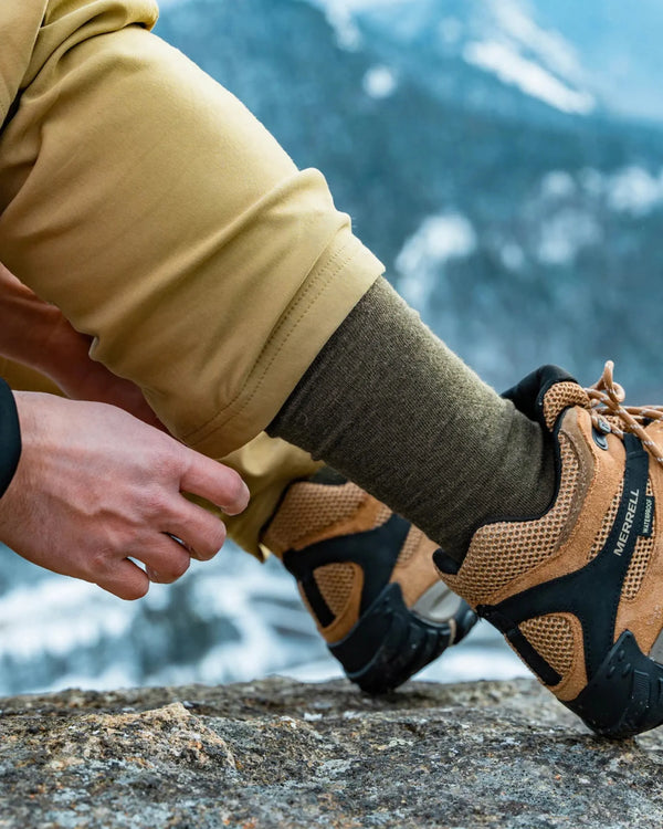 Side close-up of Essential Crew Socks in Andean Moss showing mid-calf alpaca knit and ribbed texture with hiking boot and mountain background