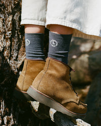 Side view of Essential Crew Socks in dark grey showing alpaca fabric and PAKA logo worn with brown suede boots outdoors