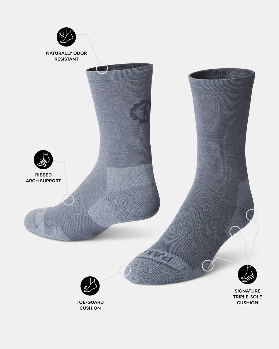 Three-quarter view of Essential Crew Socks in indigo showing toe guard, ribbed arch support, and naturally odor resistant callouts