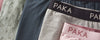 Close-up flat lay of PAKA underwear showcasing branded elastic waistbands and printed alpaca patterns on a neutral background