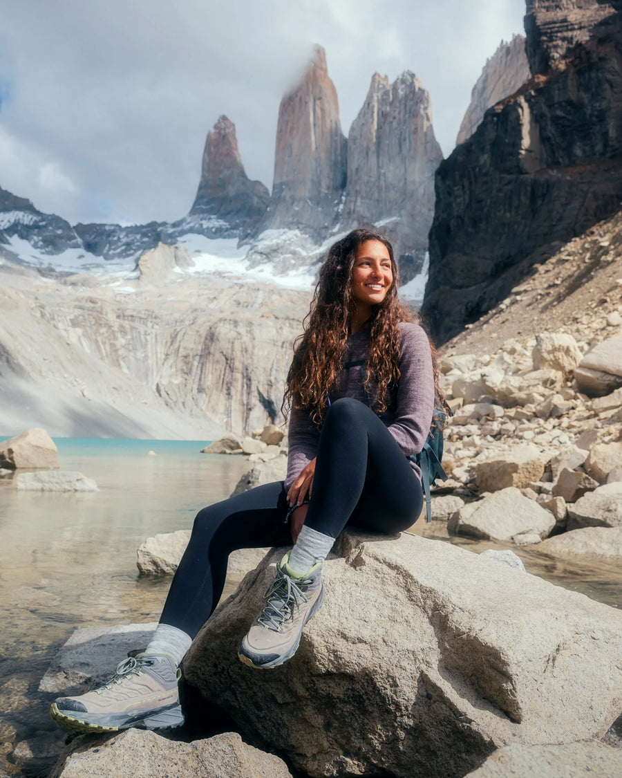 Female Hiker on Rock by Lake in Front of Jagged Mountains Wearing The Original Crew Alpaca Sweater in Flint / Light Brown – PAKA Apparel