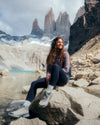Female Hiker on Rock by Lake in Front of Jagged Mountains Wearing The Original Crew Alpaca Sweater in Flint / Light Brown – PAKA Apparel