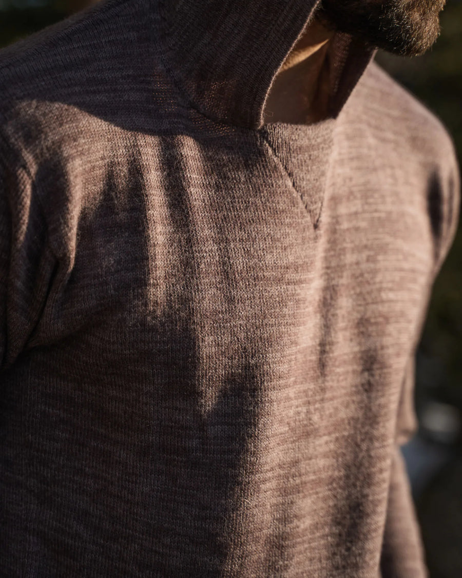 Close-up of The Hoodie in flint showing heathered alpaca knit texture and ribbed hood seam in warm sunlight