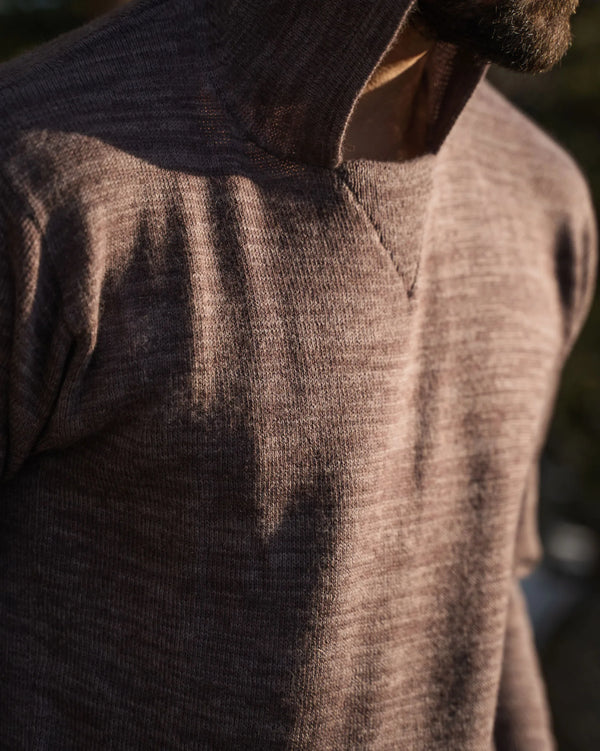 Close-up of The Hoodie in flint showing heathered alpaca knit texture and ribbed hood seam in warm sunlight