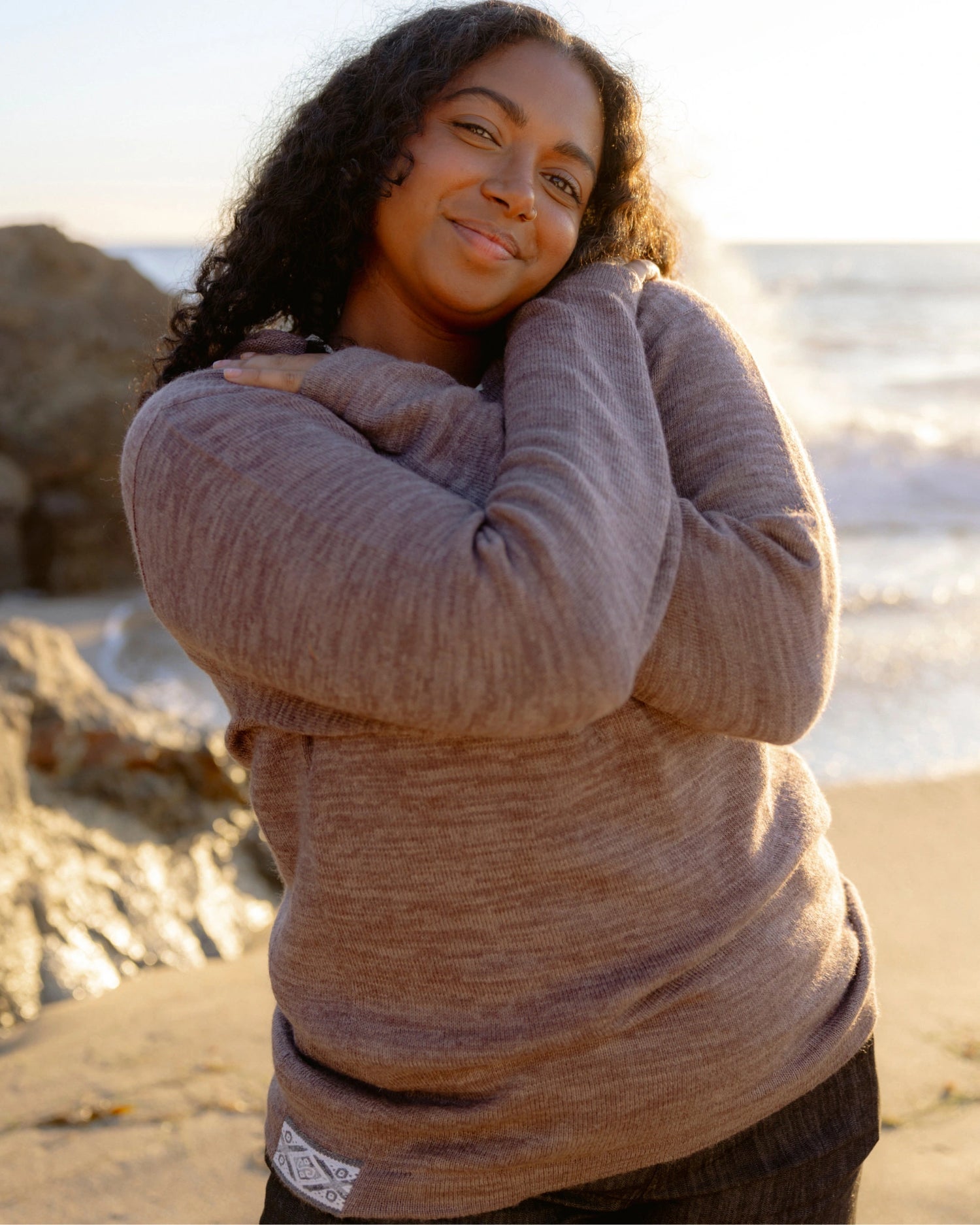 Woman Named Meghna in The Hoodie Flint Sweater Hoodie posting on the beach – PAKA Apparel