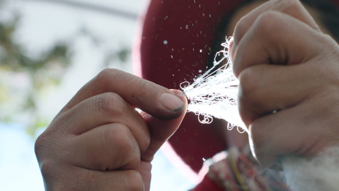 Close-up of hands grading alpaca fiber by touch outdoors, backlit