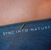 Small worm crawling across a pair of women’s underwear with the waistband text Sync Into Nature on a white background