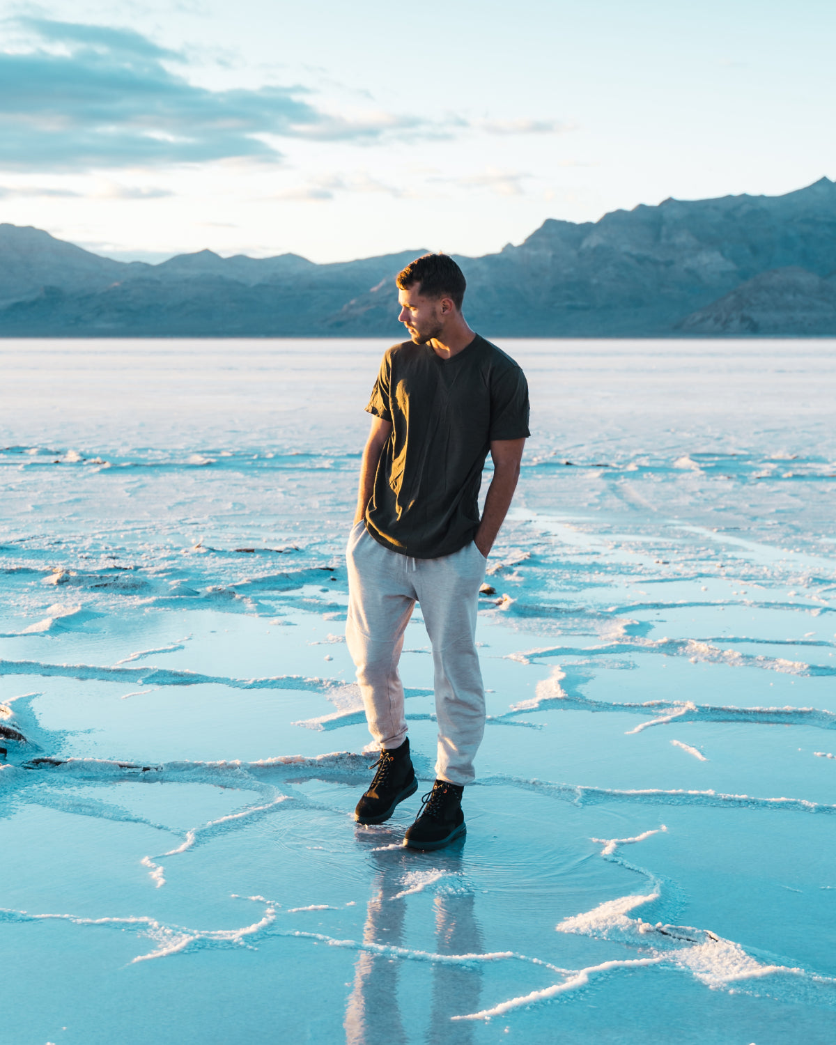Man Named Nash Wearing Green Alpaca Outdoor T-Shirt on Salt Flats Reflecting the Sky with Mountains in Background – PAKA Apparel