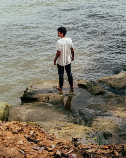 Man Named Sebastian Standing on Rock by the Sea in White Natural Alpaca Fiber T-Shirt – PAKA Apparel