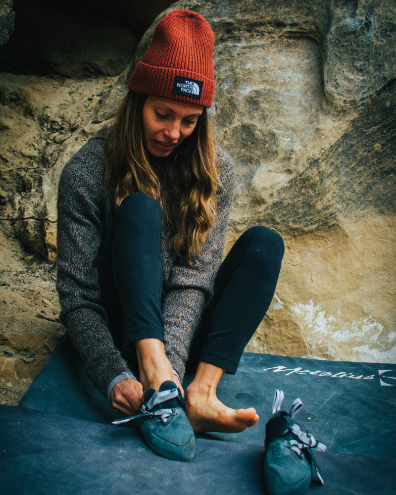 A lady putting on her shoes wearing one of our Vida hoodies