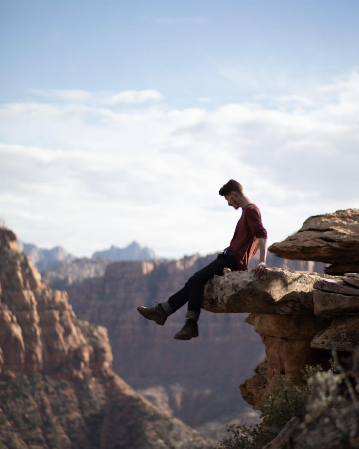 Man Named Josh Sitting on Rock Outcropping in Canyon Wearing Clay / Red Aire Long Sleeve Shirt – PAKA Apparel