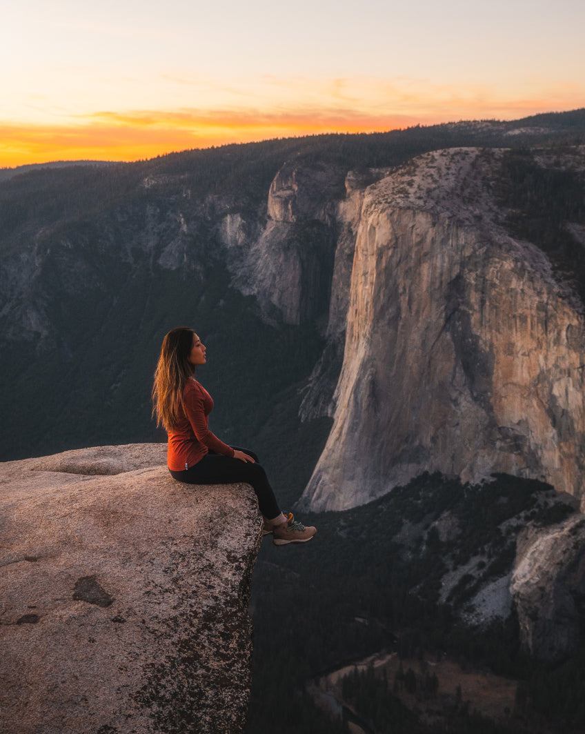 Woman Named Grace Sitting on Rock Outcrop Overlooking Vast Canyon at Sunset in Aire Clay / Red Long Sleeve Shirt – PAKA Apparel