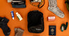 Black upcycled packing cube surrounded by travel items on orange background