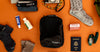 Black upcycled packing cube surrounded by travel items on orange background