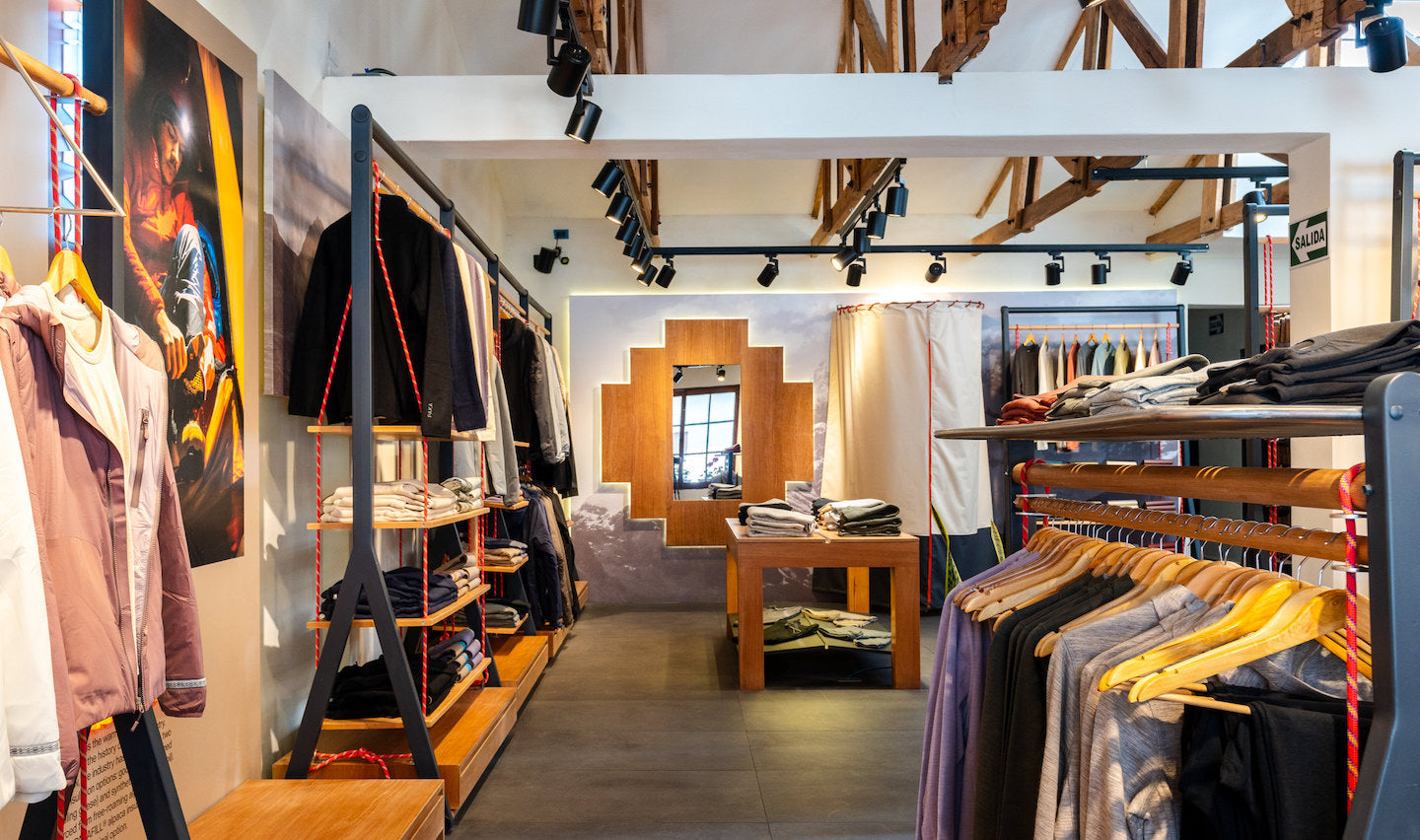 Clothing displays and racks inside PAKA flagship store in Cusco with wooden fixtures, folded sweaters, and a decorative stepped window