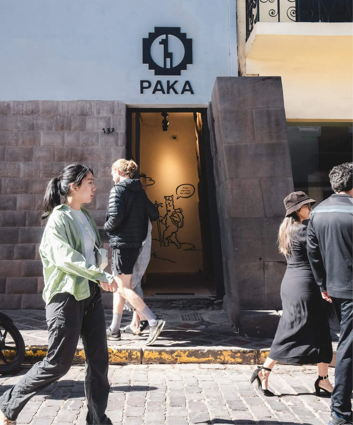 PAKA flagship store entrance on Plaza de Armas in Cusco with open doorway, stone Inca wall, and people outside