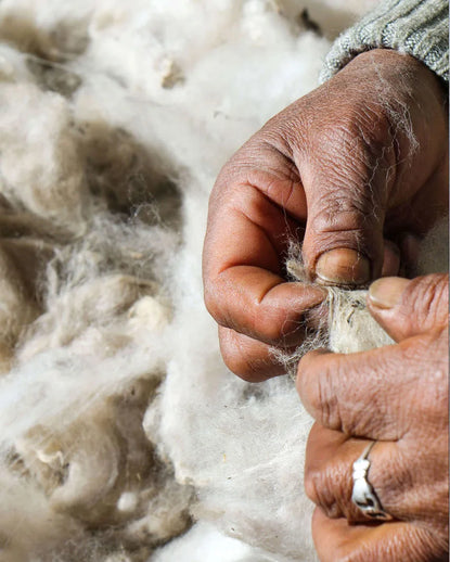Close-up of a woman sorting loose white alpaca fiber by hand