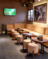 Paka flagship store café seating area showing wooden tables, round stools, and alpaca artwork on the wall
