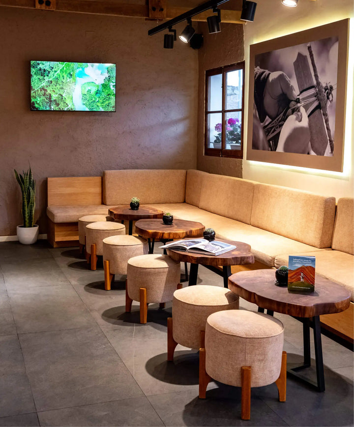 Paka flagship store café seating area showing wooden tables, round stools, and alpaca artwork on the wall
