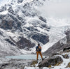A hiker carrying a backpack looking up at Ausangate.