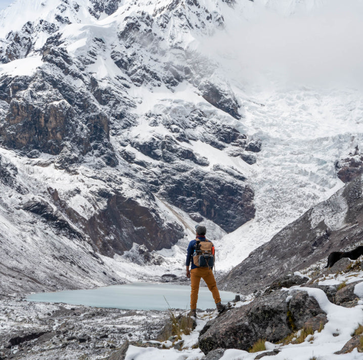 A hiker carrying a backpack looking up at Ausangate.