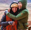 Two climbers on a sandstone cliff in Moab wearing PAKAFILL jackets looking out over red cliffs