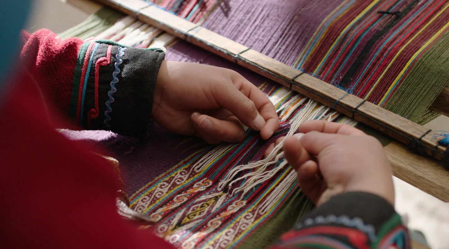 Hands of a Quechua woman weaving colorful blanket